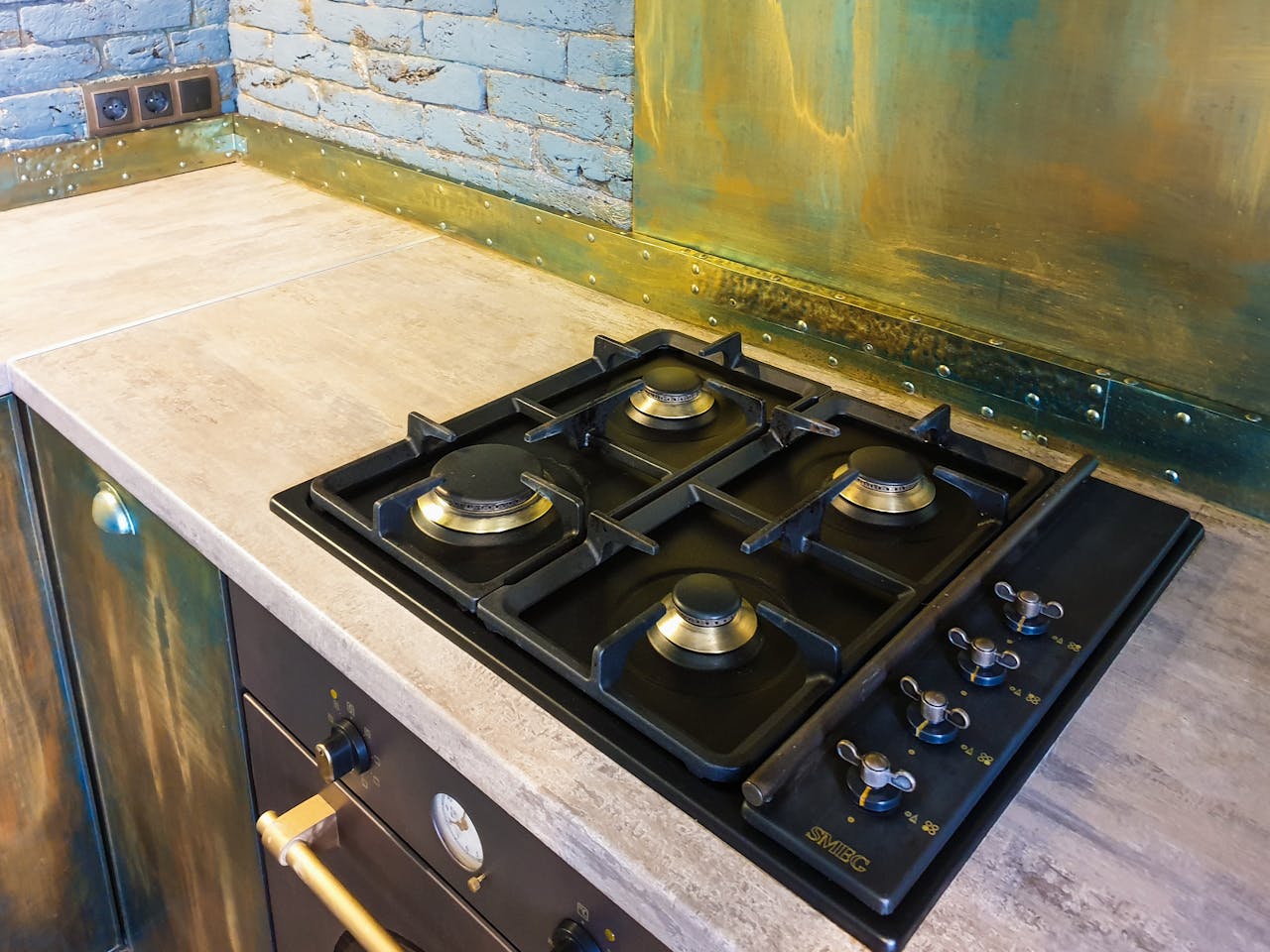 Home Close-up of a sleek modern gas stove on a rustic industrial style kitchen counter.